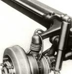 Detail zavěšení pravého předního kola, kde je dobře vidět torzní tyč, uloženou podél rámu. Kulový čep zavěšení předního kola i kloub hnací poloosy byly uzavřeny v gumových manžetách.